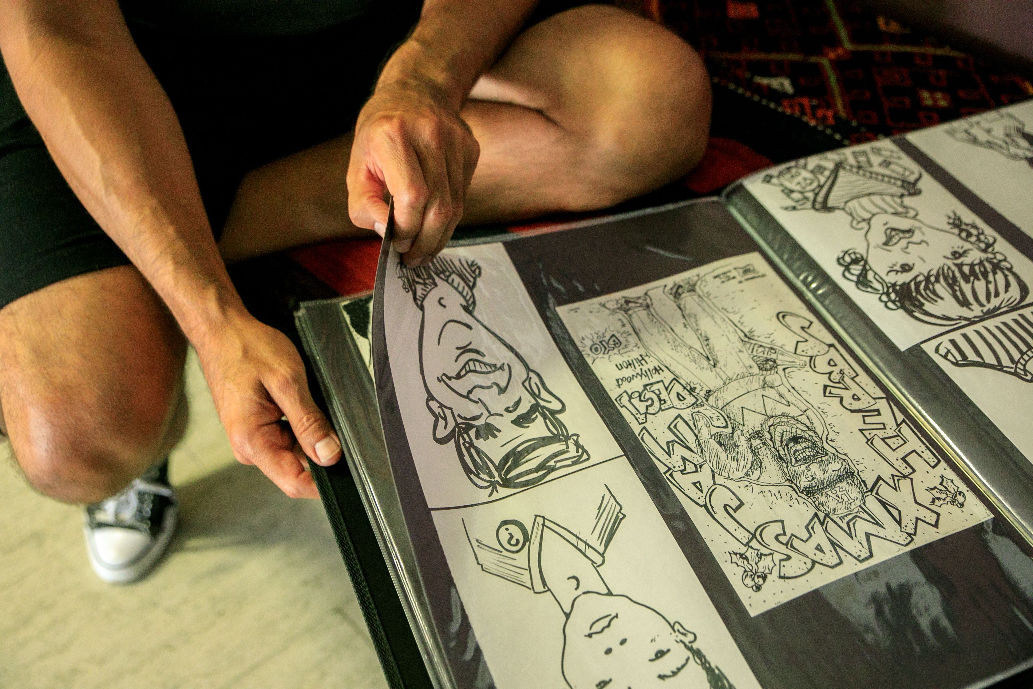 Person turning pages of a printed comic art album, showcasing sequential comic panels